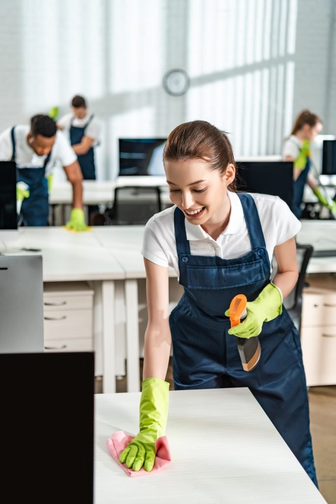 cheerful cleaner in overalls cleaning office desk with rag-eves cleaning utah